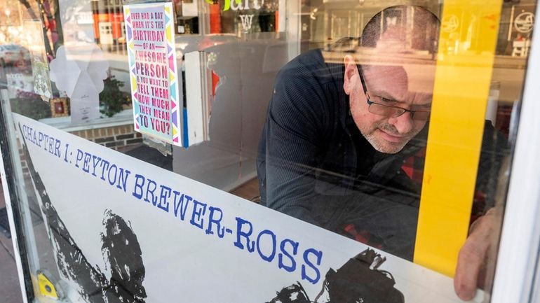 Peter Precourt levels a sign in the front window for...