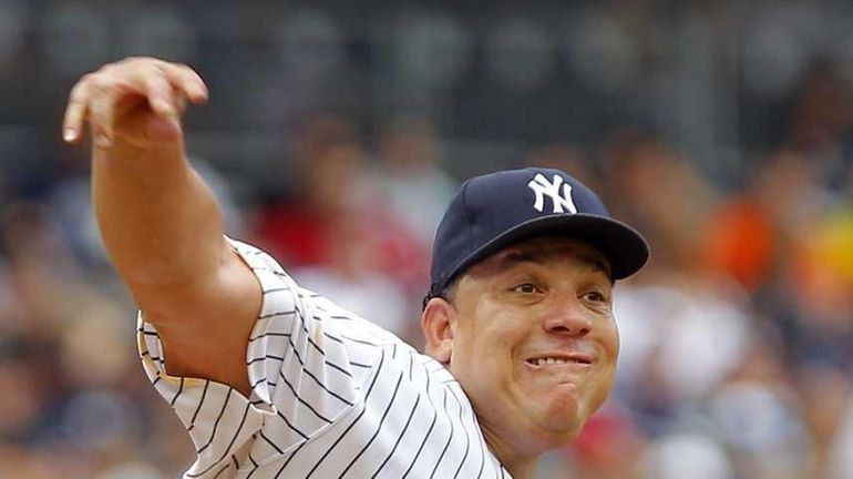 New York Yankees pitcher Bartolo Colon throws to first base...