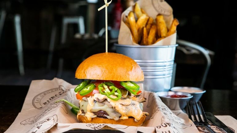 An elk burger with pepper jack cheese, lettuce, tomato, sautéed mushrooms,...