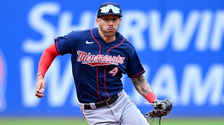 The Twins' Carlos Correa fields a ground ball hit by the...