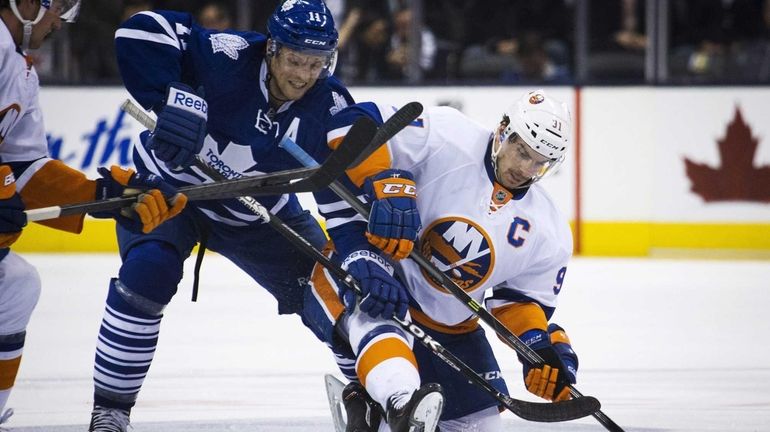 Toronto Maple Leafs' Jay McClement, left, battles for the puck...