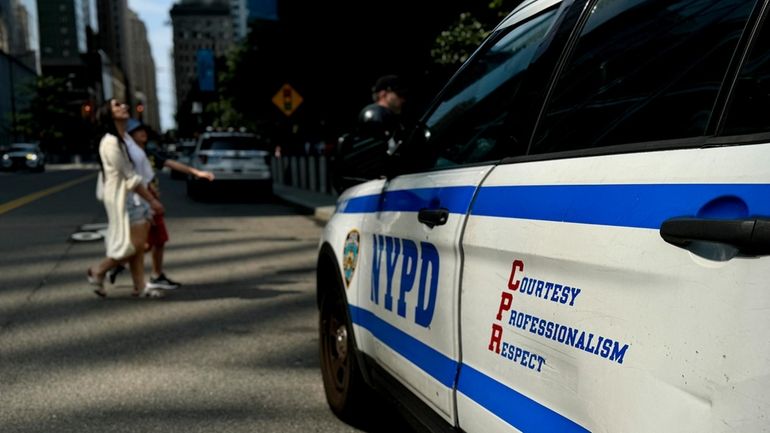 Pedestrians pass in front of a New York Police Department...