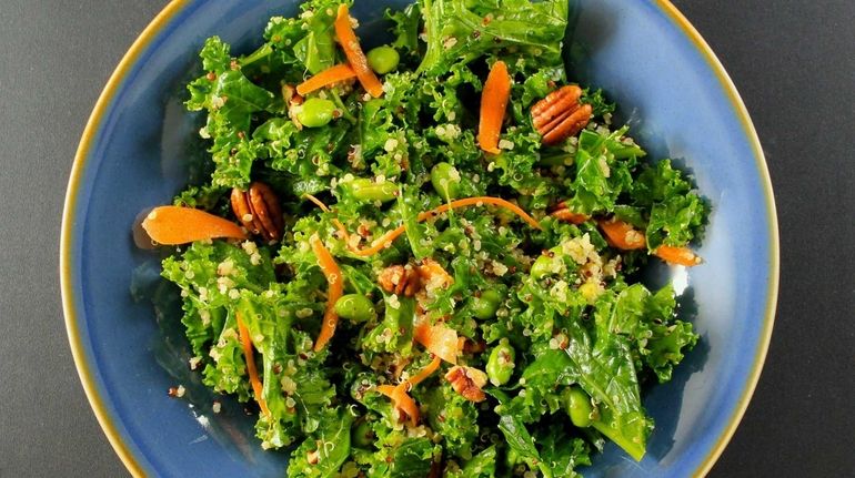 Kale, shredded carrots, cooked quinoa, toasted pecans and edamame in...