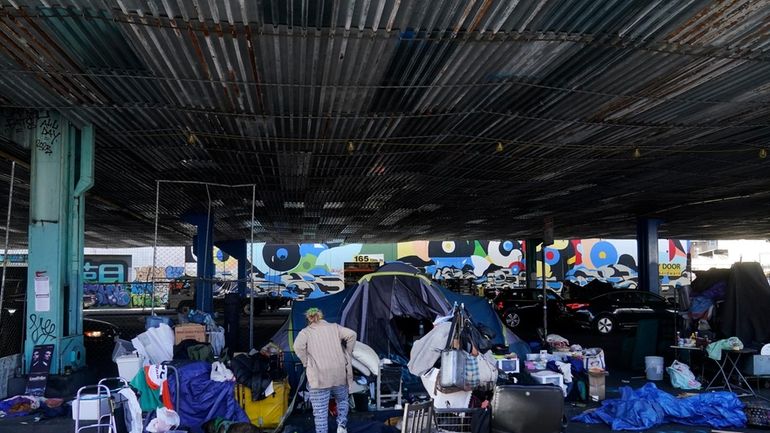 A woman gathers possessions to take before a homeless encampment...