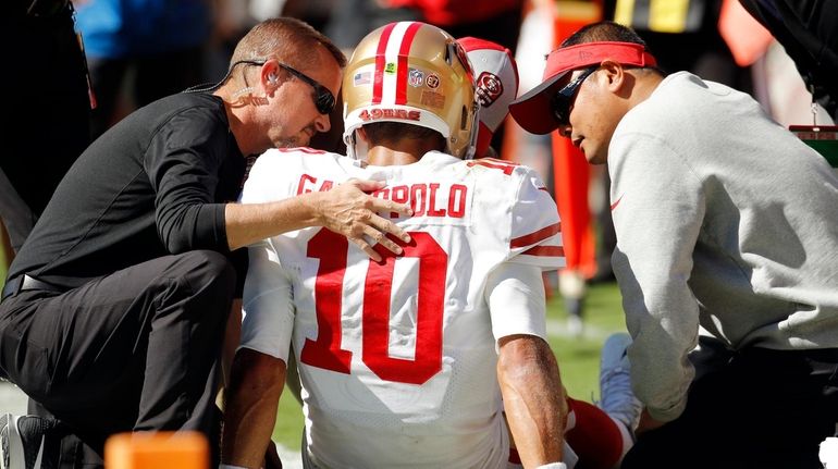 Trainers attend to 49ers quarterback Jimmy Garoppolo who was injured after...