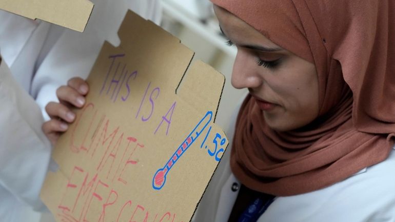 Sarah Neggazi holds a sign that reads "this is a...