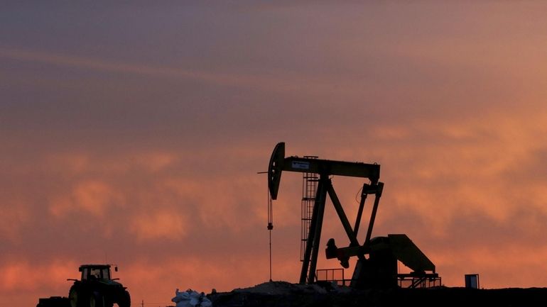 A well pump works at sunset on a farm near...