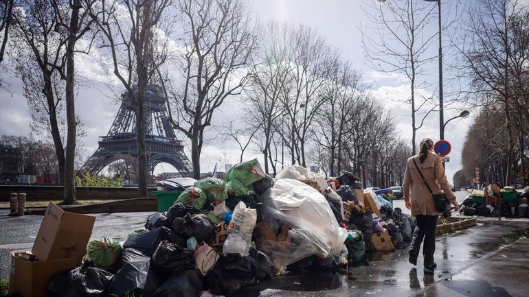 A woman walks past a pile of uncollected garbage near...