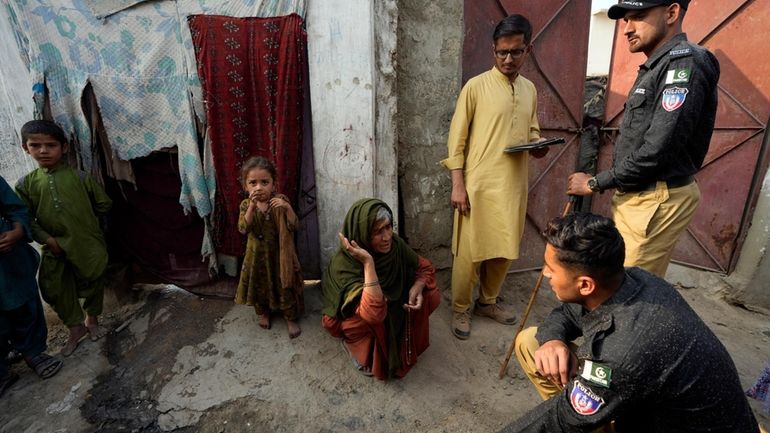 Pakistani police officers conducts biometric identification of a resident during...