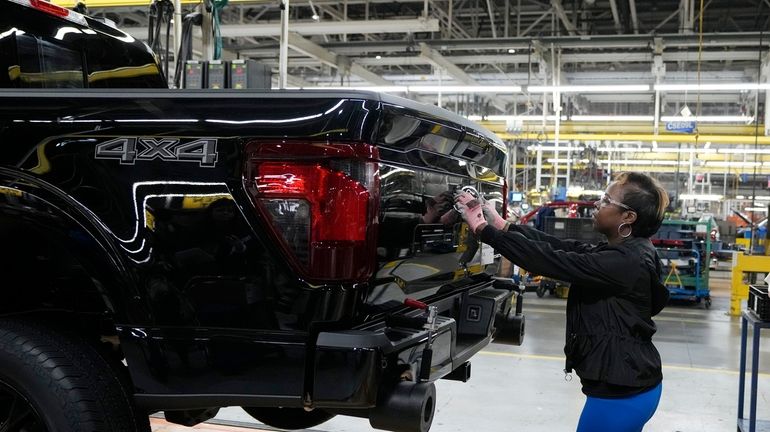 Assembly line worker Lashunta Harris applies the Ford logo on...