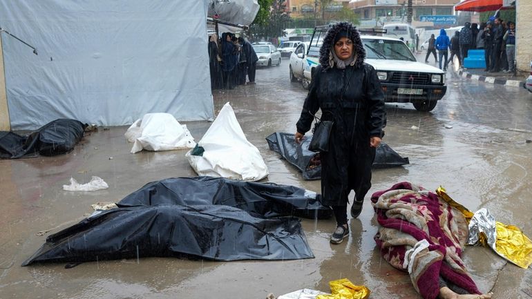 A woman walks between dead bodies of Palestinians killed in...