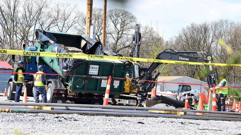 Crews load a dumpster with concrete blocks containing toxic chemical drums at...