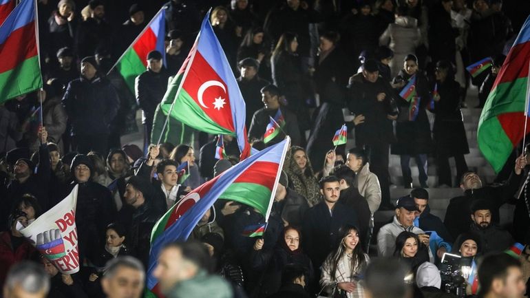 People wave national flags celebrating Azerbaijan's President Ilhan Aliyev's victory...