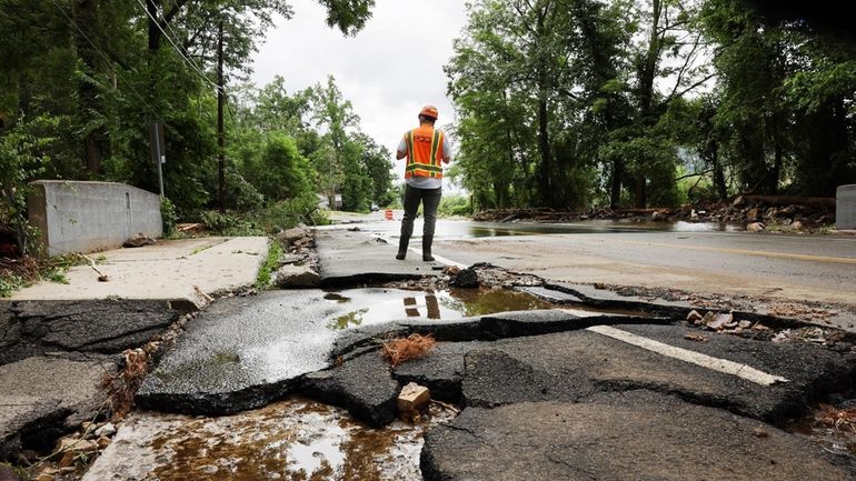 Workers survey a severely damaged road near Bear Mountain State...
