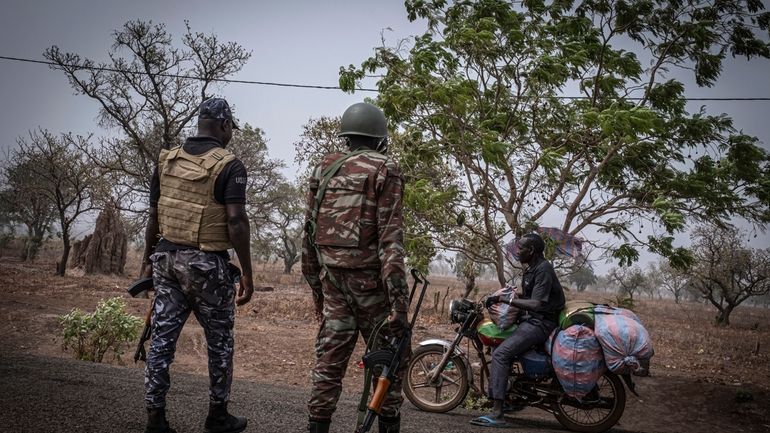 FILE-A police officer and a soldier from Benin stop a...