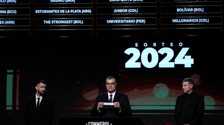 Competitions Director of Conmebol Frederico Nantes, center, holds a paper...