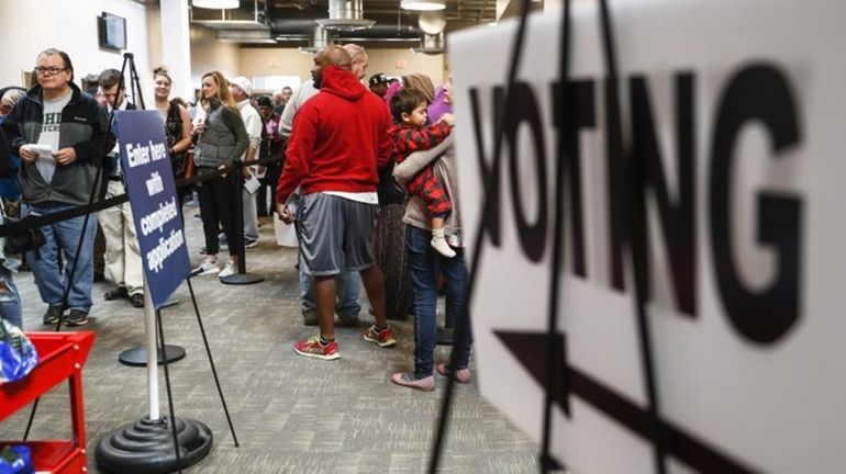 A line of early voters wait in queue at the...