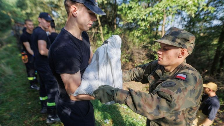 Soldiers fill and arrange sandbags to help strengthen the embankments...