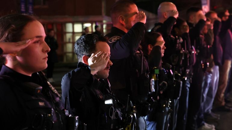 Police officers salute as the bodies of two officers are...