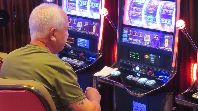 A gambler smokes while playing a slot machine at the...