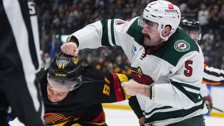 Minnesota Wild's Jacob Middleton, right, and Vancouver Canucks' Dakota Joshua...