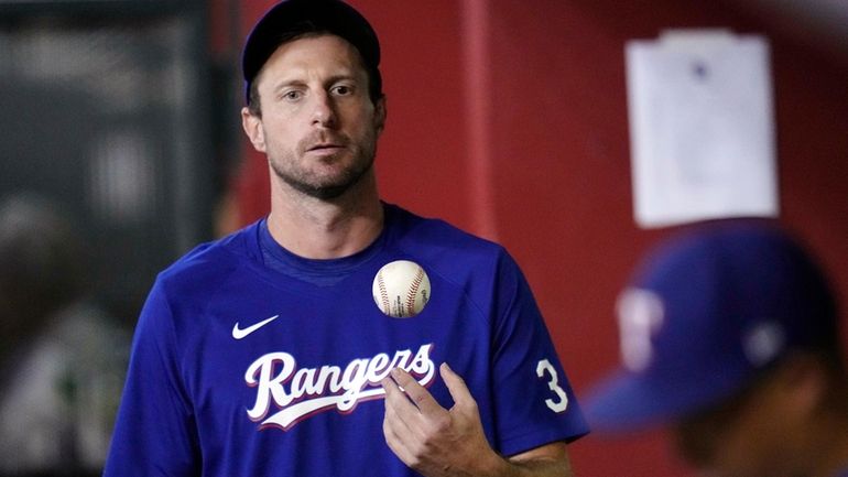 FILE- Texas Rangers' Max Scherzer flips the ball in the...