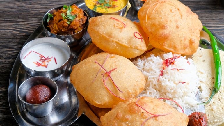 Thali featuing puffed bread pillows with a variety of colorful chutneys...