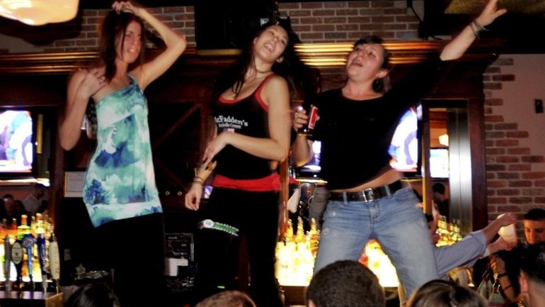 Young women stand on the bar to sing at McFadden's...