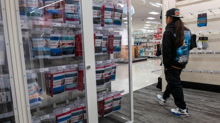 Products are locked behind glass as a person shops at...