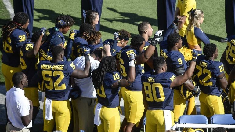 Michigan football players raise their fists up in protest during...