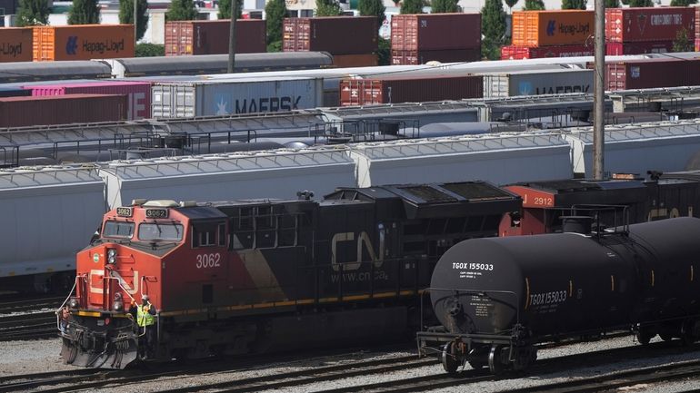 Employees are seen on a locomotive being moved at the...