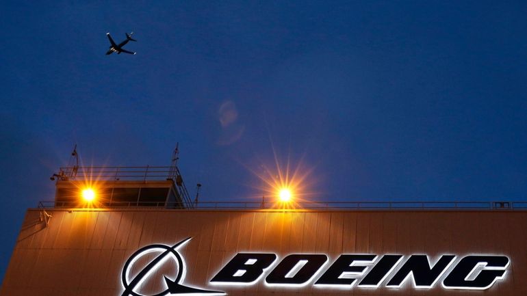 An airplane flies over a sign on Boeing's newly expanded...