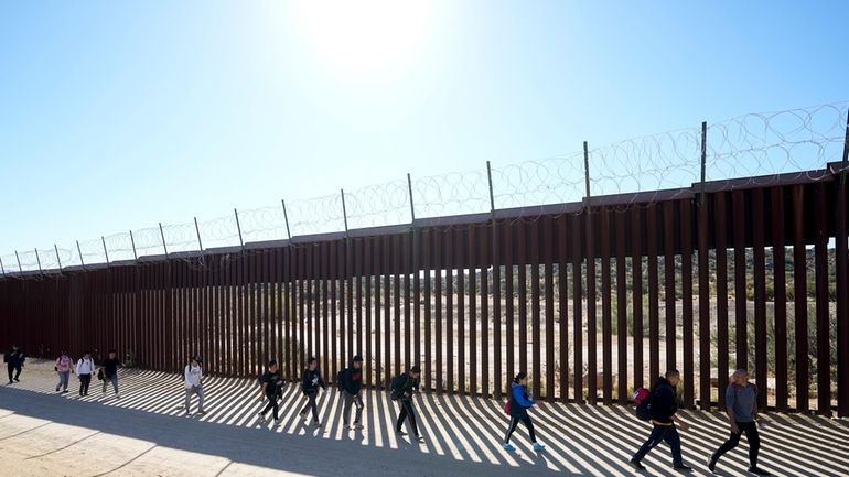 A group of people, including many from China, walk along...