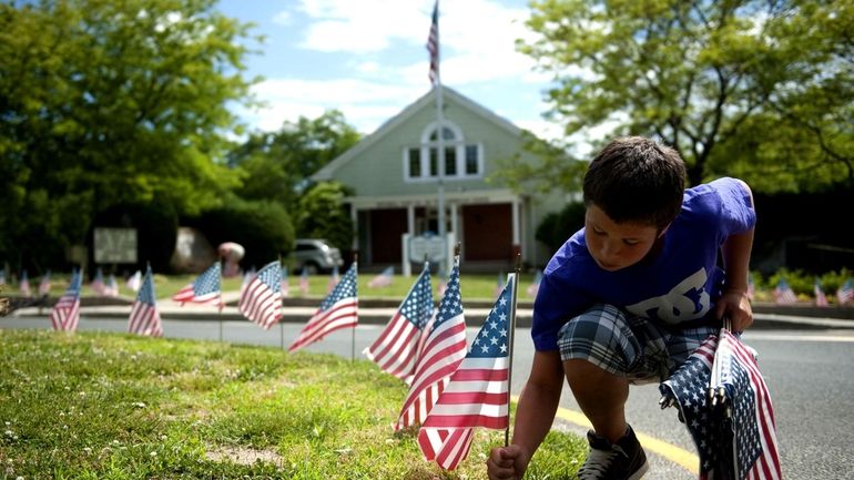 A child places flags in the ground in honor of...