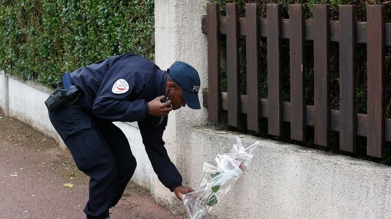 A French police officer lays flowers while paying tribute to...