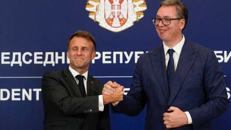 French President Emmanuel Macron clasps hands with Serbian President Aleksandar...