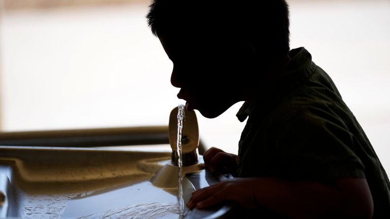 A student drinks from a water fountain at an elementary...