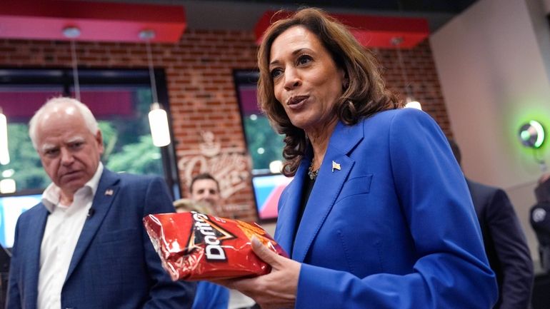 Democratic presidential nominee Vice President Kamala Harris holds a bag...