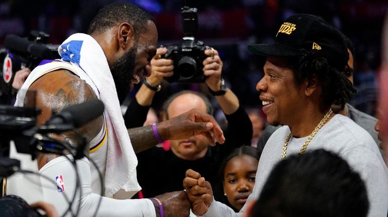 Lakers forward LeBron James, left, greets rapper Jay-Z after a...