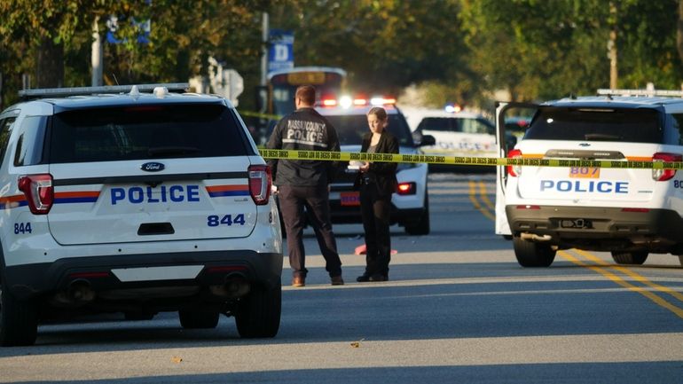 Nassau County police officers respond to the scene of the...