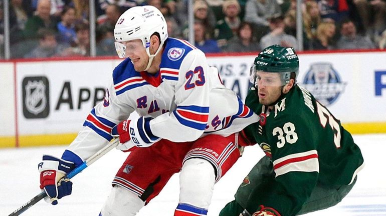 Rangers defenseman Adam Fox controls the puck as Wild right...