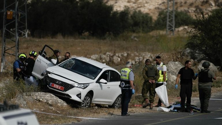 Israeli security forces and rescue services check the scene of...