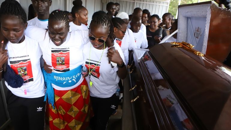 Relatives try to comfort a woman crying after viewing the...