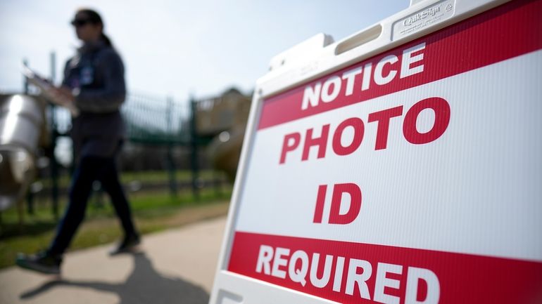 A Super Tuesday voter walks past a sign requiring a...