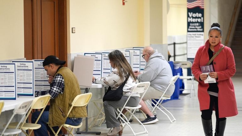 A woman walks with her ballot to a vacant voting...