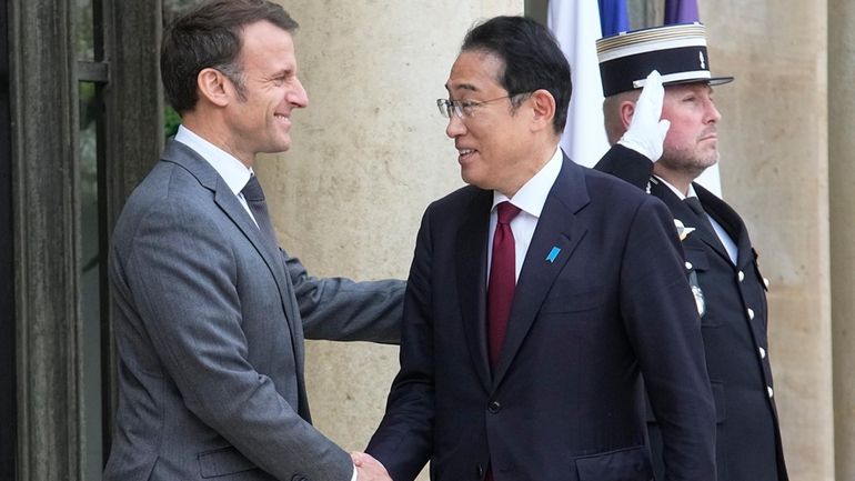 French President Emmanuel Macron, left, shakes hands with Japanese Prime...