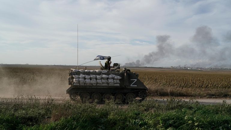 Israeli soldiers patrol as the smoke rises from the Gaza...