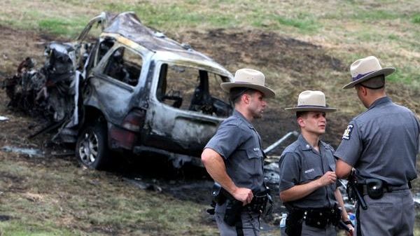 Officers investigate the scene of a three-car accident, which killed...