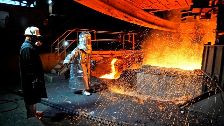 A worker in a protective suit pokes a metal rod...