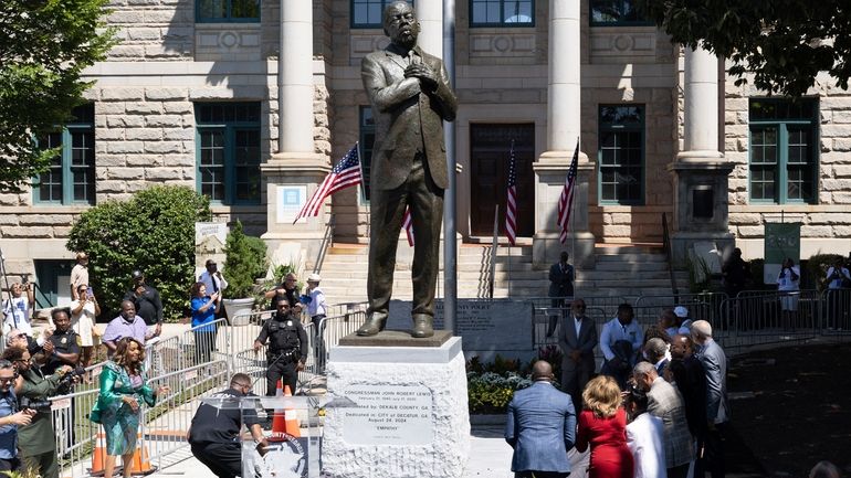 People stand around the statue honoring the late civil rights...